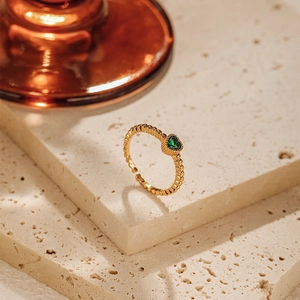 Detail of 18K gold plated heart green zircon ring with elegant beaded edge texture