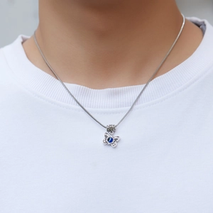 Detailed close-up of a silver butterfly pendant necklace with a blue evil eye stone