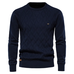 Macro view of navy blue crew neck sweater showing knit diamond pattern and brand tag