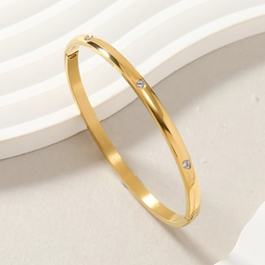 Detailed view of gold-plated bangle with three inset cubic zirconia and hinge clasp