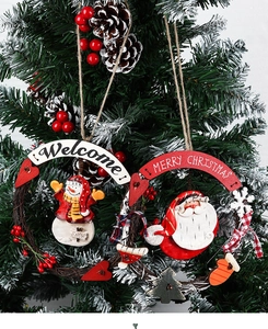 Detail of Christmas wreath with snowman and Santa hanging on snow-dusted pine branches
