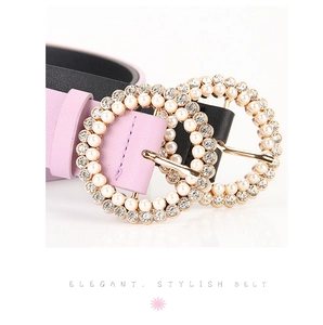Detailed macro view of gold-tone buckle with inlaid pearls and rhinestones on leather belt
