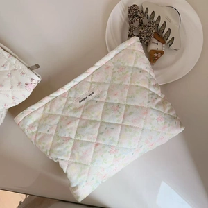 Detailed macro view of quilted floral makeup bag with simple wish woven label and cotton texture