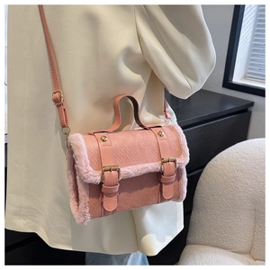 Detail of pink plush and faux leather cylindrical crossbody bag with gold hardware buckle