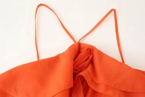 Detailed close-up of orange halter dress featuring soft mesh fabric and flower neck accent