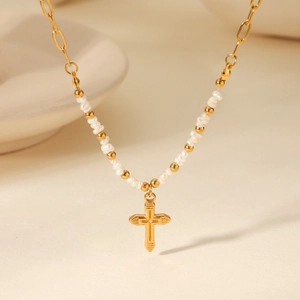 Detailed shot of freshwater pearl necklace with a gold cross pendant and steel chain