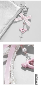 Detail of pink plaid bow, star pendant and cross on a faux pearl ribbon keychain