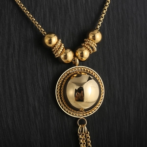 Detailed macro view of a vintage gold tassel sphere pendant on a stainless steel chain
