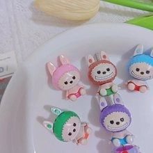 Macro detail of colorful resin bunny charms with smiling faces in a ceramic tray
