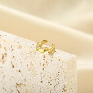 Detailed view of a gold chain-link ring resting on a beige textured stone and fabric