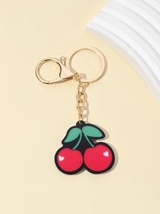 Close-up of red cherry keychain with green leaves and gold lobster clasp detail