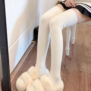 Detail of cream white over-knee socks featuring a vertical ribbed knit texture