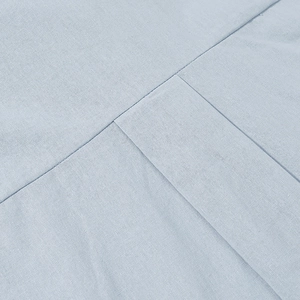 Close-up of light blue cotton linen fabric showing woven texture and stitched seam details