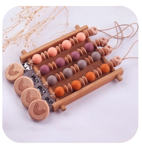 Close-up of silicone and beech wood pacifier clips with engraved rainbow on a tray