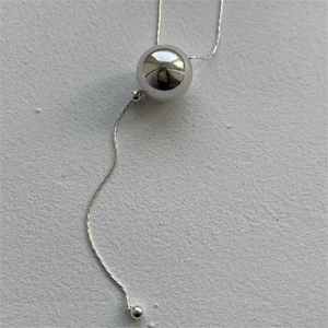 Detail of silver snake chain necklace featuring a large polished spherical ball pendant
