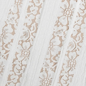 Macro shot of white lace fabric with floral patterns and pleated textures on the dress