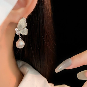Detail of butterfly pearl earring with inlaid crystals on a female model