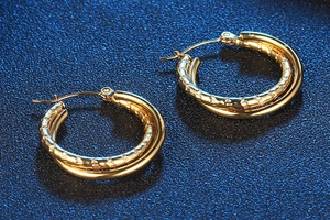 Detail of gold double-layered hoop earrings with hammered texture and polished finish