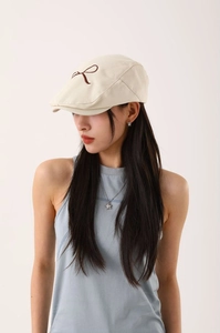 Détail du coton sergé blanc cassé de la casquette gavroche avec nœud brodé marron élégant