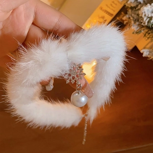 Gros plan d'un choker en peluche blanche avec un pendentif flocon argenté et une perle