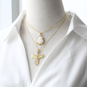 Layered gold necklace featuring a Buddha pendant and angel wings on a mannequin