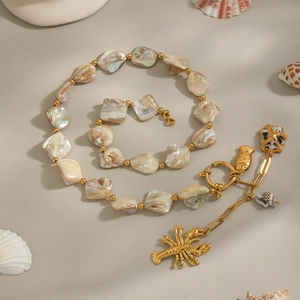 Golden ocean theme necklace with shell beads and lobster fish pendants on beige background