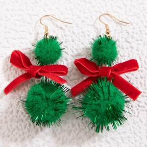 Christmas bow earrings with green pom poms and red velvet bows on a white textured background
