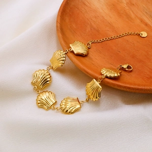 Elegant gold stainless steel shell link bracelet displayed on silk and wooden tray