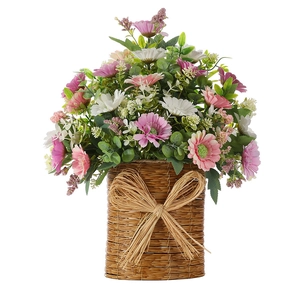 Detail of multi-color daisies and green leaves in a woven basket with raffia bow