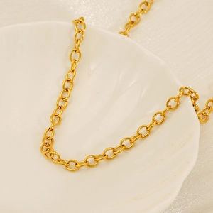 Golden stainless steel O-chain necklace featuring polished oval links on a ceramic plate