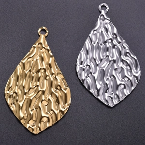 Macro view of teardrop pendants with hammered texture in gold and silver steel finish