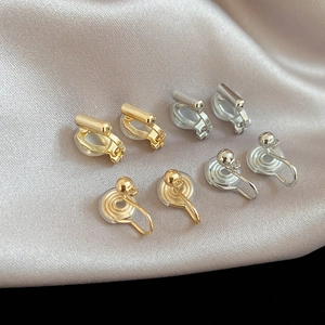 Detail of gold and silver geometric ear clip converters on a silk background