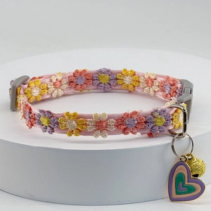Detail of colorful floral lace cat collar with heart pendant and gold bell accessory