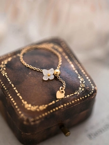 Close-up of golden white clover chain ring with heart pendant on vintage leather case
