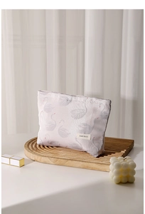 Close-up of pink fabric cosmetic bag with swan jacquard and H&R BAG woven label