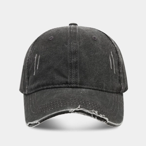 Detailed view of black distressed denim baseball cap with frayed brim and washed texture