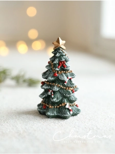 Macro shot of miniature green resin Christmas tree with fake snow and festive ornaments