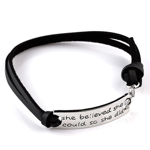 Detail of inspirational engraved quote on black leather bracelet with silver metal plate