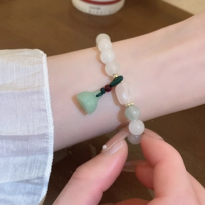 Close-up of a Neo-Chinese style bracelet with green beads and a lotus seed pod pendant