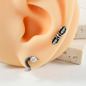 Detail of vintage silver vajra stud and teardrop zircon piercing on a silicone ear model