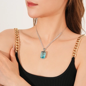 Detail of a square blue gemstone pendant on a sparkling silver tennis chain necklace