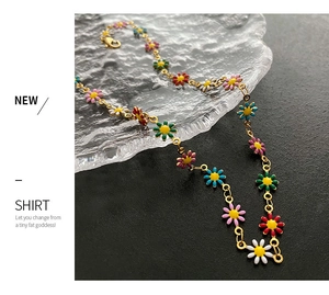 Detailed macro view of colorful enamel daisy charms on a gold-plated link necklace chain