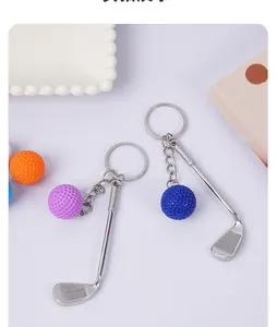 Macro view of mini metal golf club and textured ball keychain with ring attachment