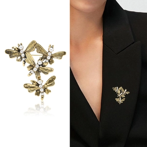Vintage golden dragonfly brooch with pearls shown on white background and black blazer