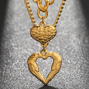 Golden double-layered angel wing heart pendant necklace on a premium black background