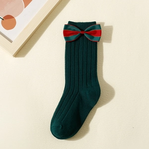 Detail of dark green baby knee high socks with red and green stripe festive bow