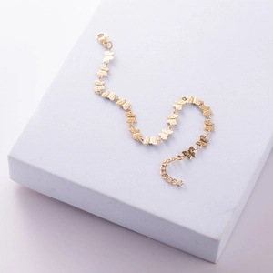 Close-up of golden stainless steel butterfly bracelet with lobster clasp on stone stand