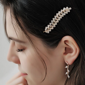 Detail of crystal leaf bridal hair clip and matching earrings set on female model