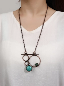 Detail of vintage bronze necklace with turquoise and deep green stones on a model