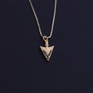 Close-up of gold arrow pendant with black zircon inlays on a black box chain link